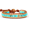 Turquoise and gold beaded bracelet with brown leather strap on a white background