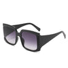 A pair of square oversized sunglasses with a bold retro chic design, featuring a black frame and pink lenses, displayed on a marble surface.