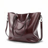 Burgundy leather handbag with a shoulder strap on a white background