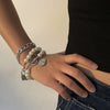 Hand wearing multiple bracelets with pearls and charms from ramodo jewelry store on a neutral background