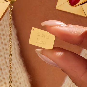 Gold tag with 'Love You' engraving held by a hand against a warm-toned background