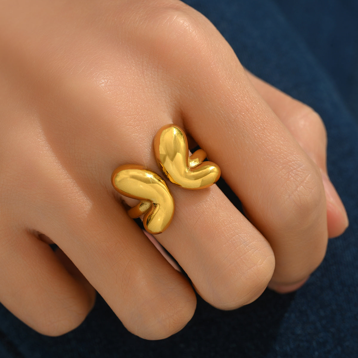 tiktok trendy Gold butterfly ring on a finger against a dark background