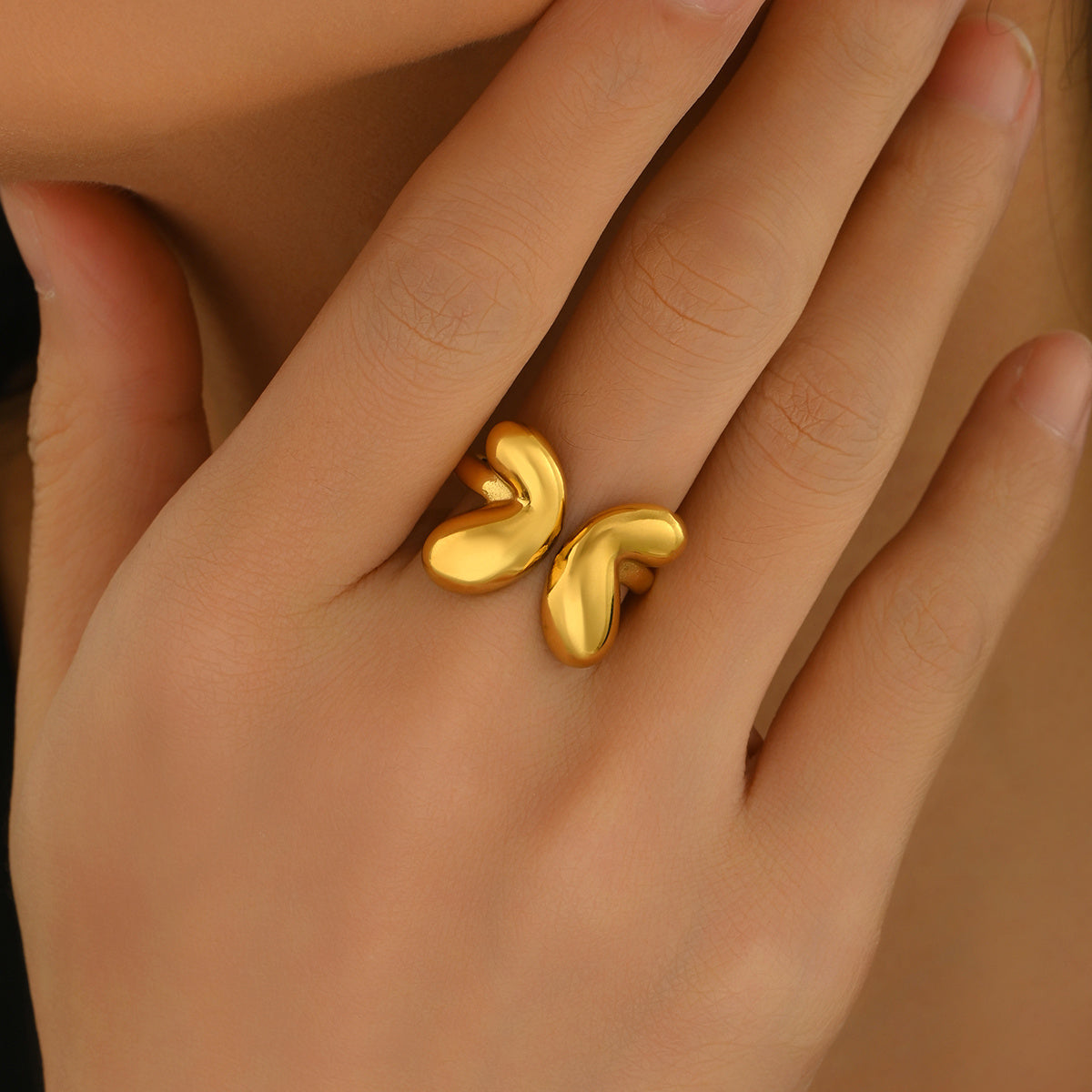 tiktok trendy Gold butterfly -shaped ring on a hand against a neutral background