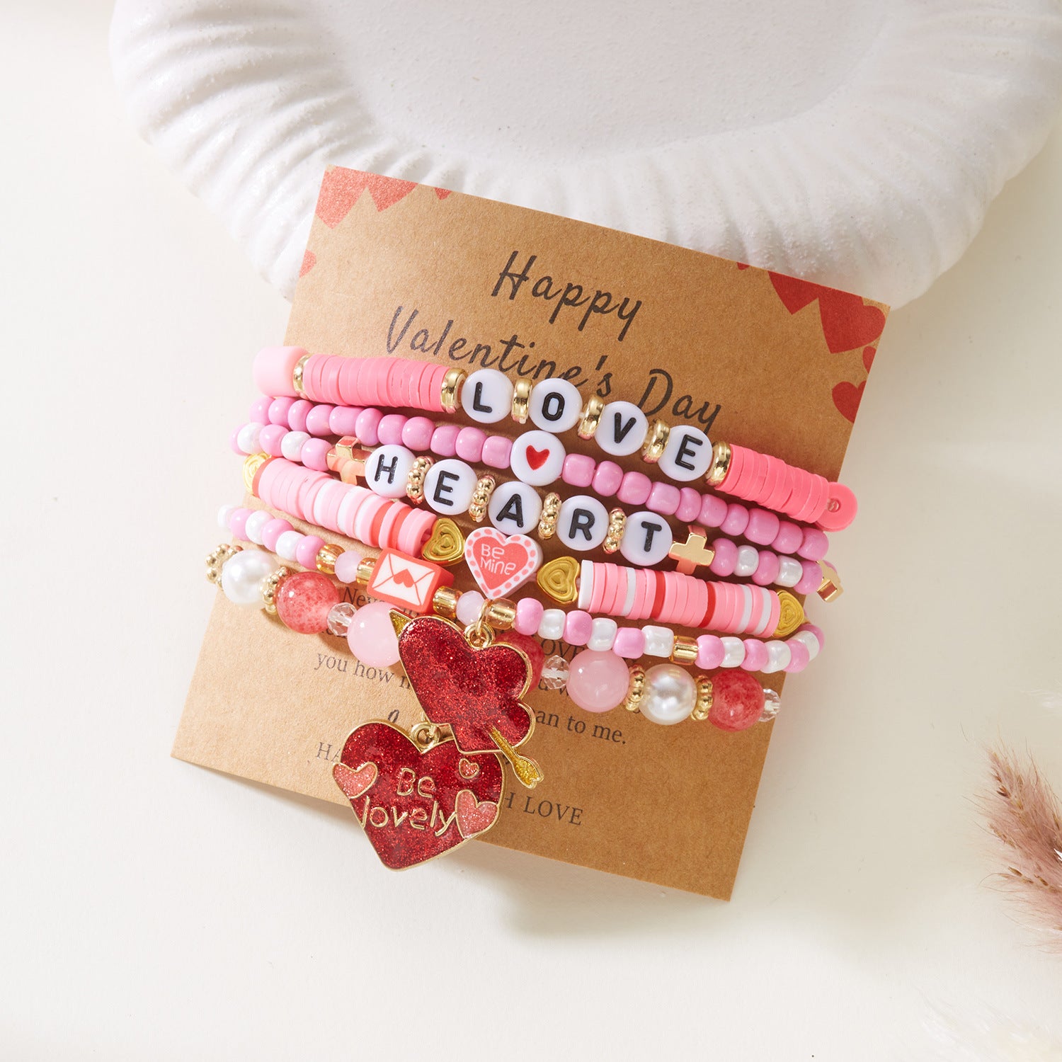 Set of colorful bracelets with heart and letter charms on a Valentine's Day card.