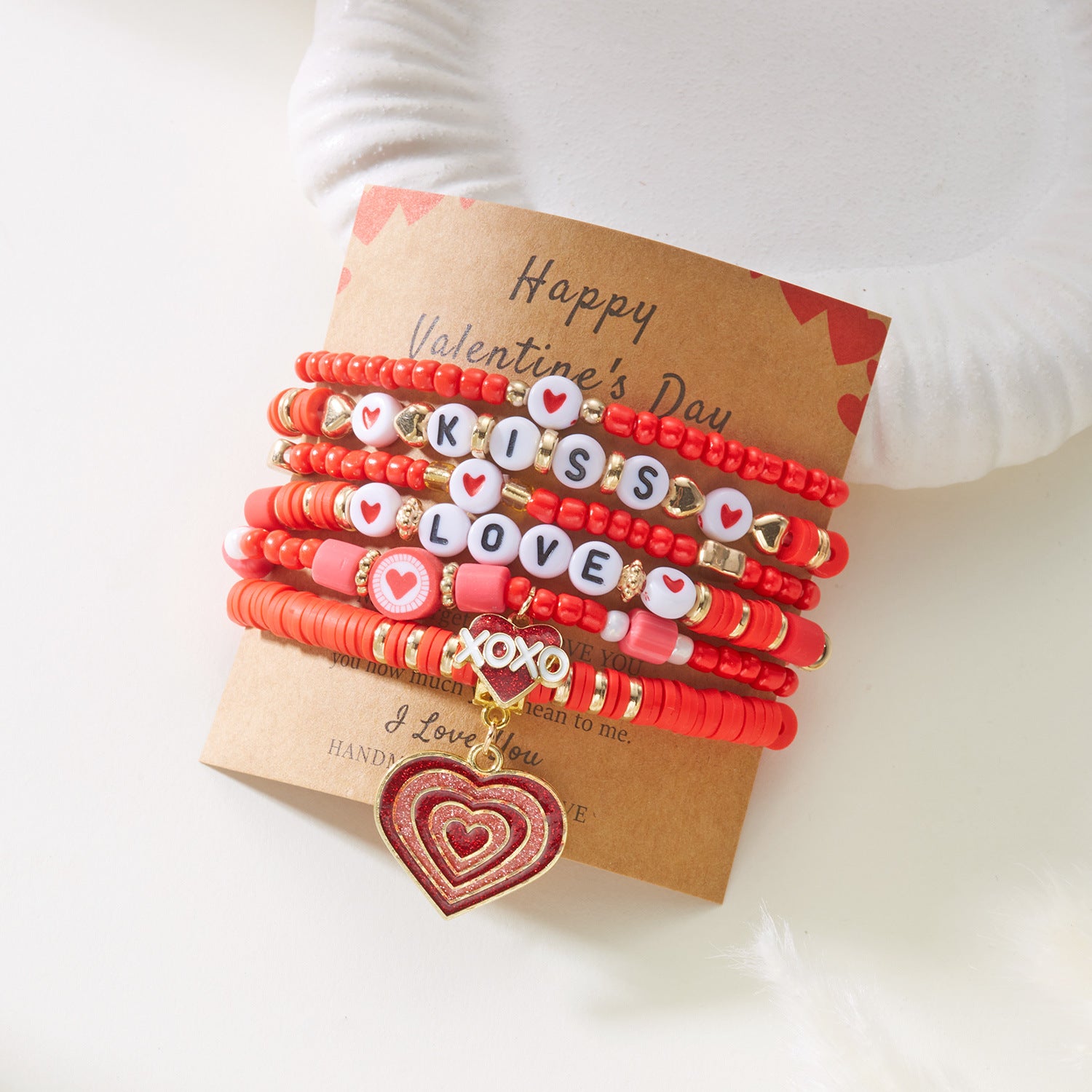 Set of red beaded bracelets with letter charms on a 'Happy Valentine's Day' card.