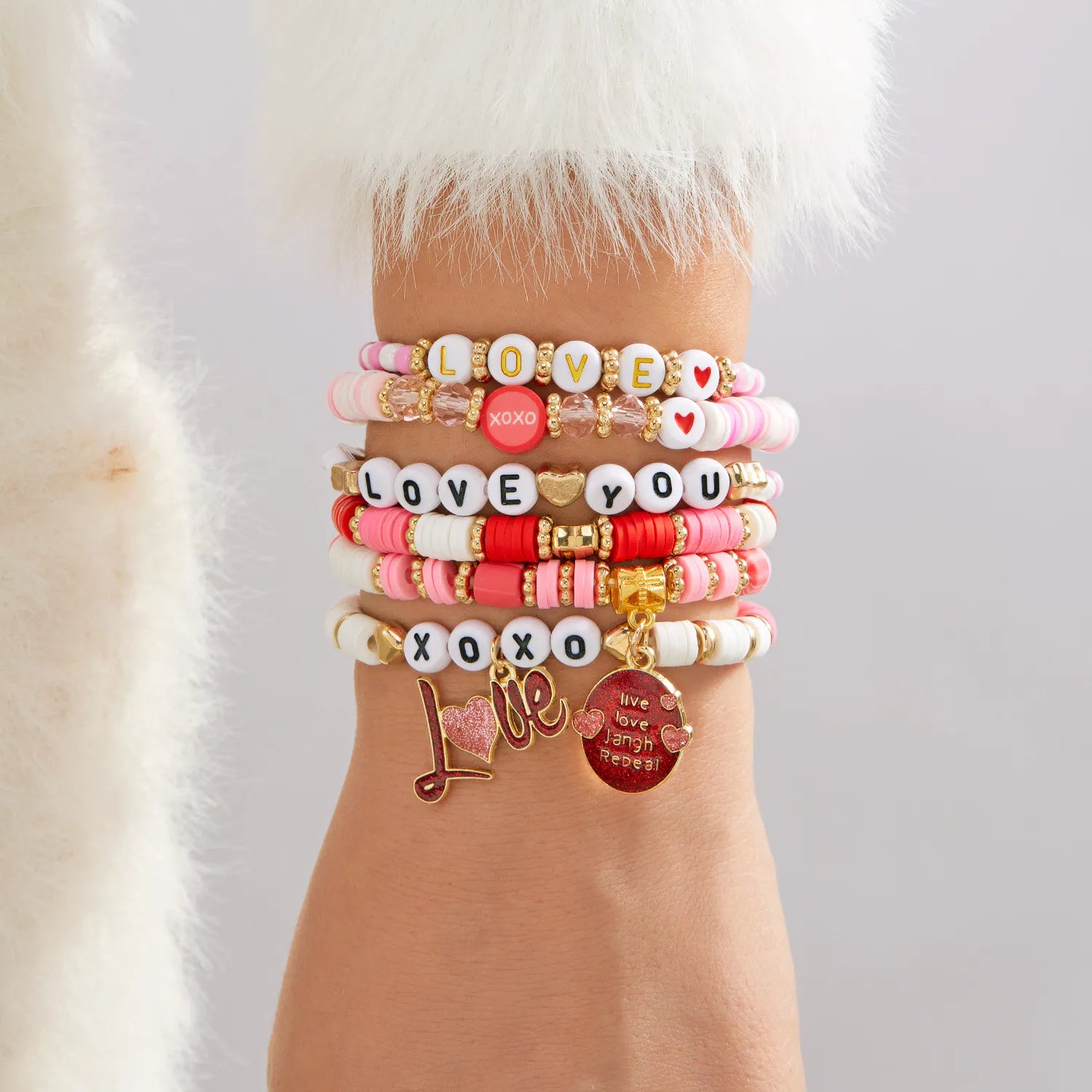 Stack of colorful bracelets with charms on a wrist against a neutral background