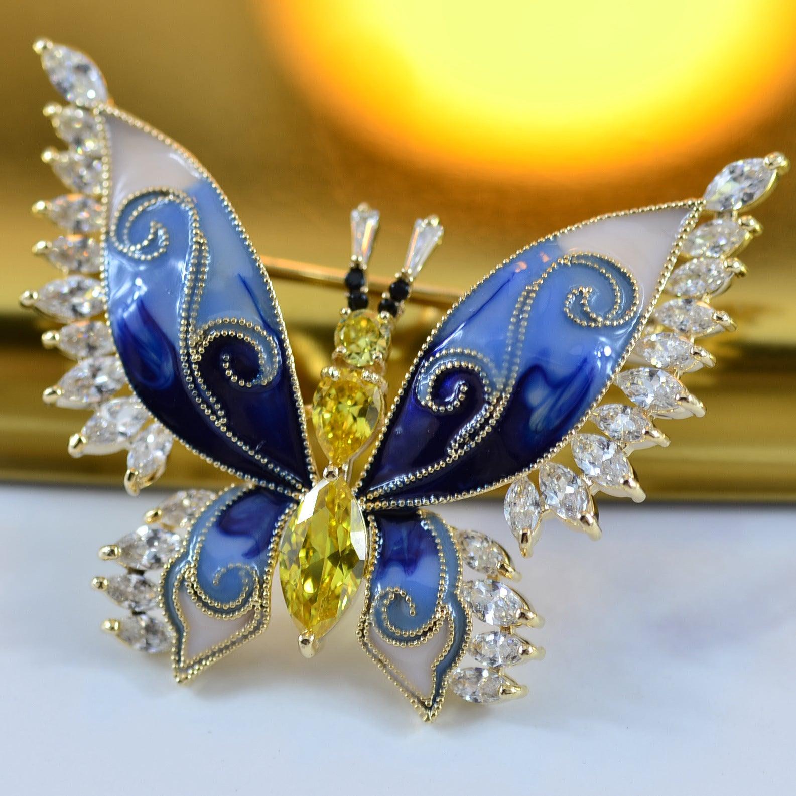 A vibrant blue and white butterfly-shaped brooch with gold details and CZ gemstones.