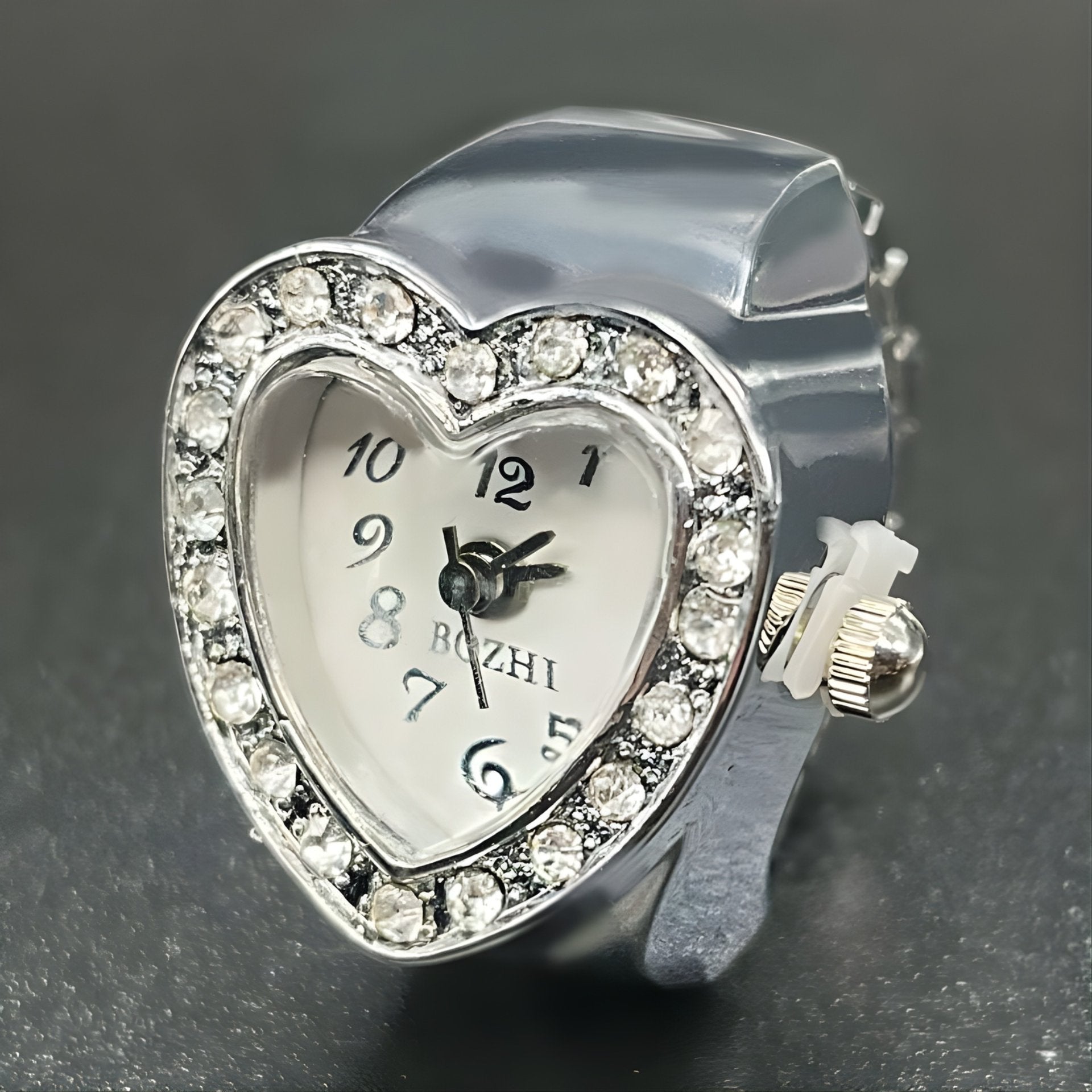 A heart-shaped ring watch with sparkling crystals, displayed in silver color.