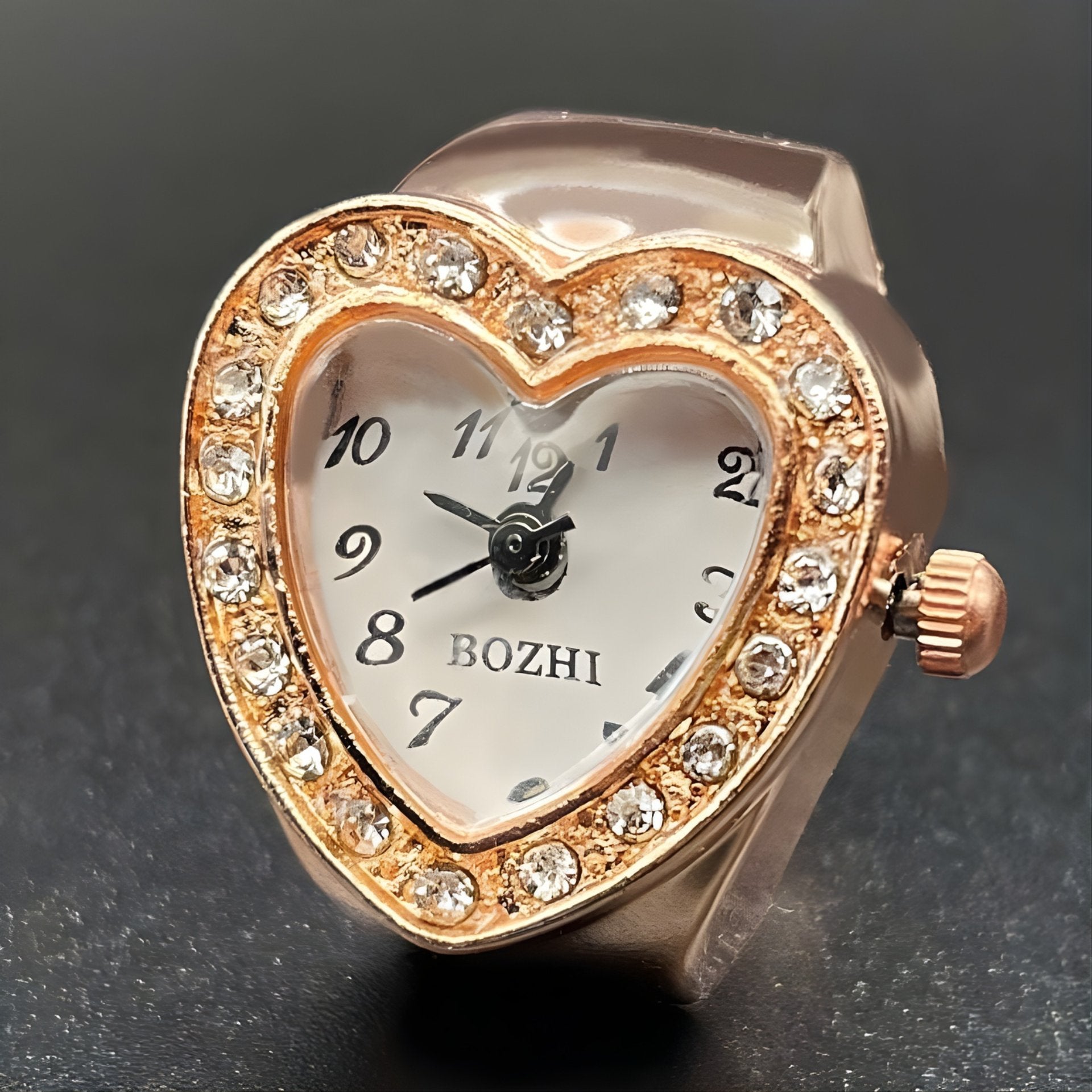 A heart-shaped ring watch with sparkling crystals, displayed in rose gold color.