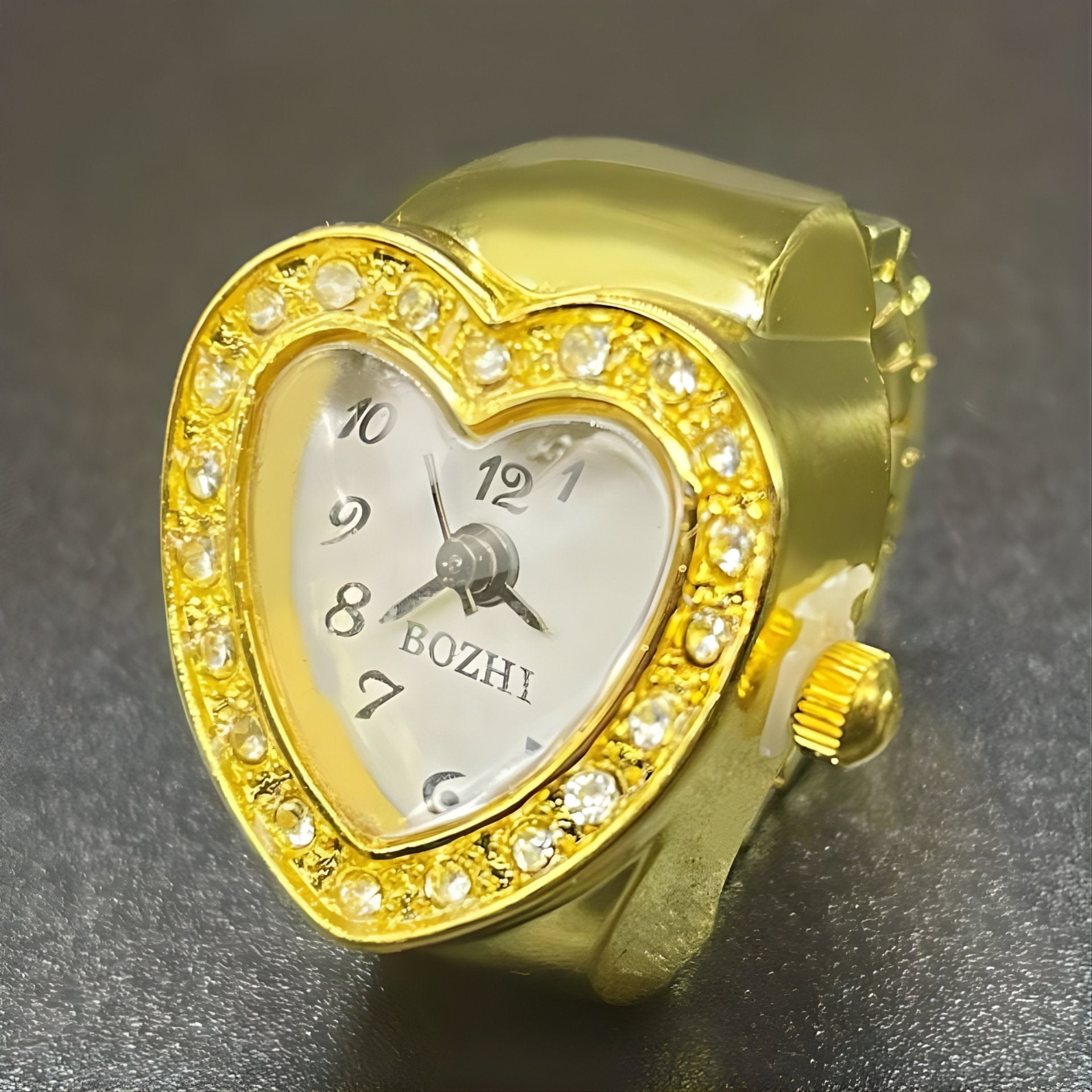 A heart-shaped ring watches with sparkling crystals, displayed in gold color.