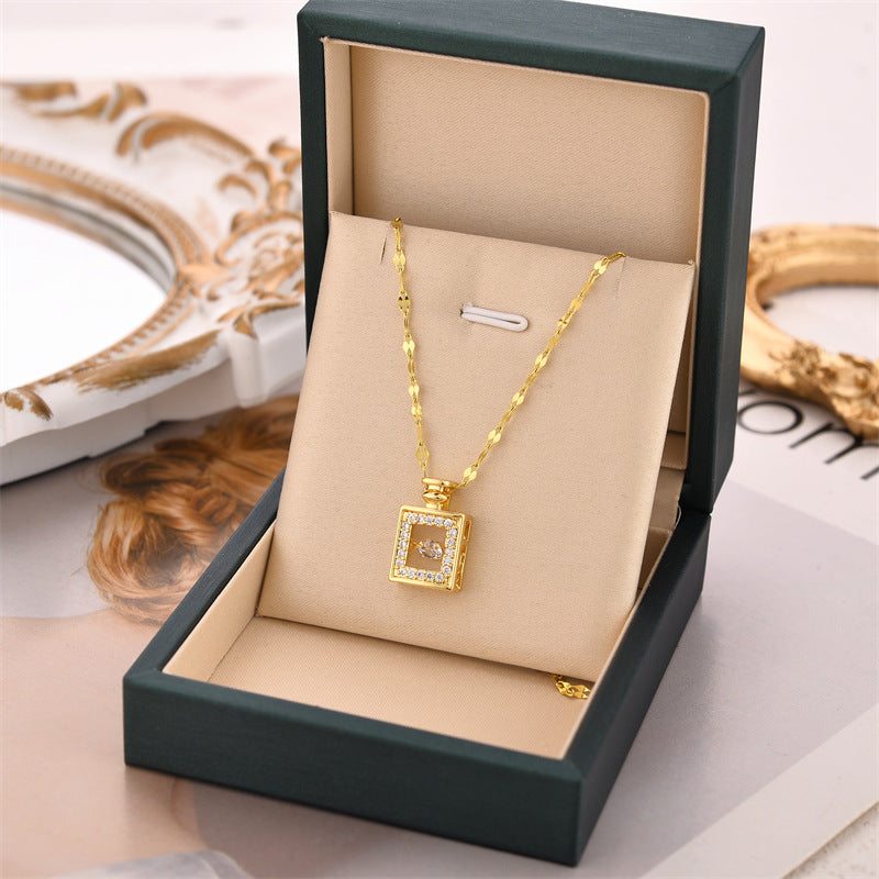 Gold necklace with a square pendant in an open jewelry box on a decorative surface.