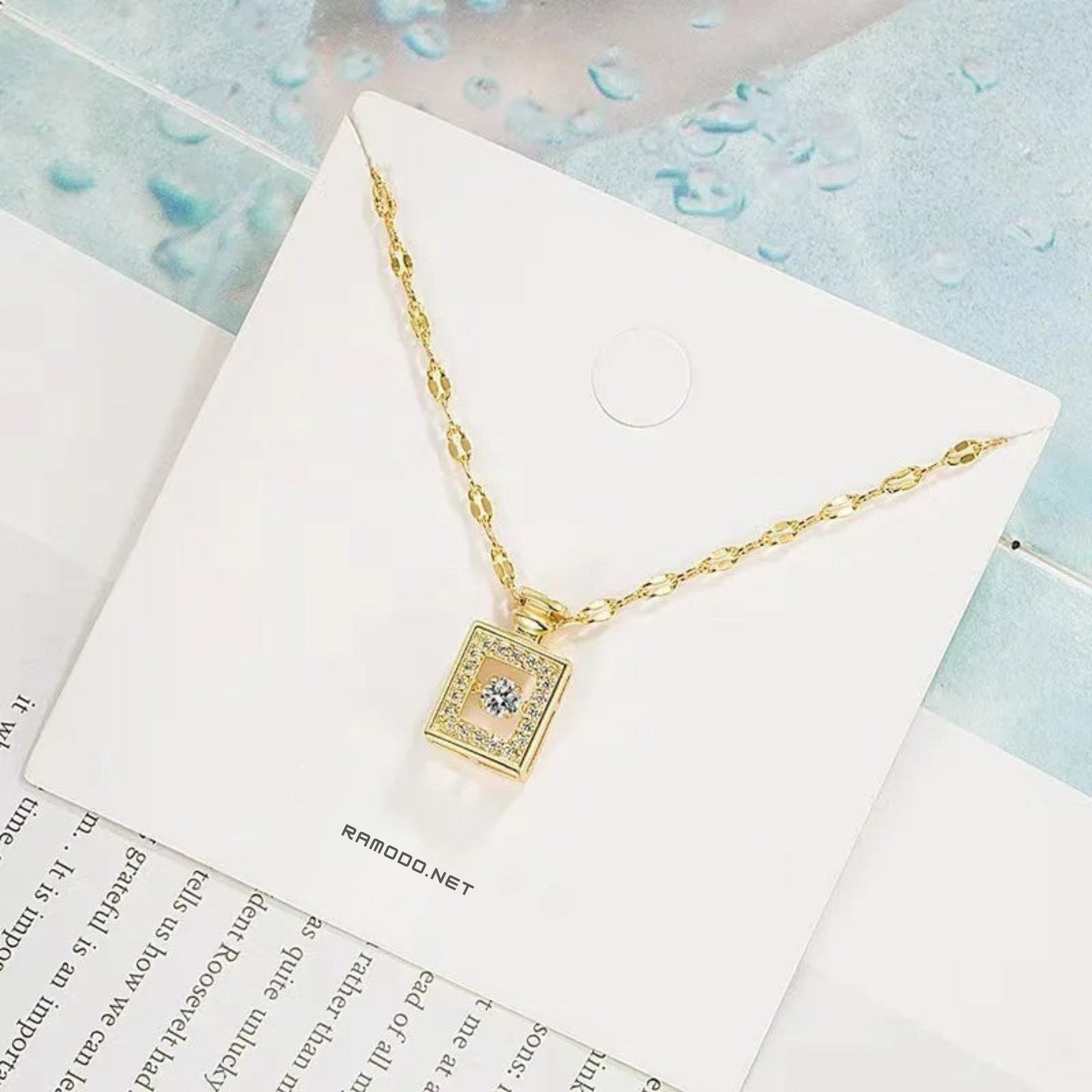 Gold necklace with a square pendant on a branded card with 'nyun' branding.