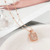 Rose gold necklace with a square pendant on a white surface