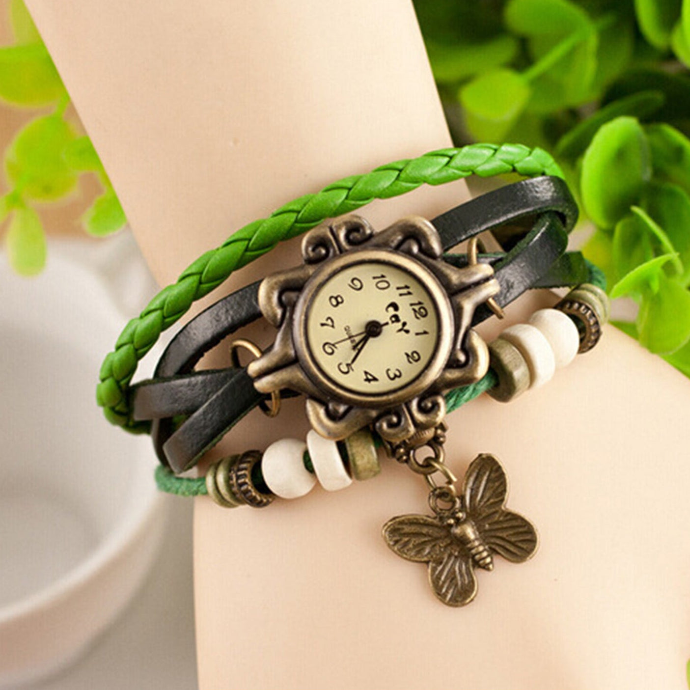 Multicolored braided bracelet with a vintage-style watch face and butterfly charm on a wrist against a natural background.