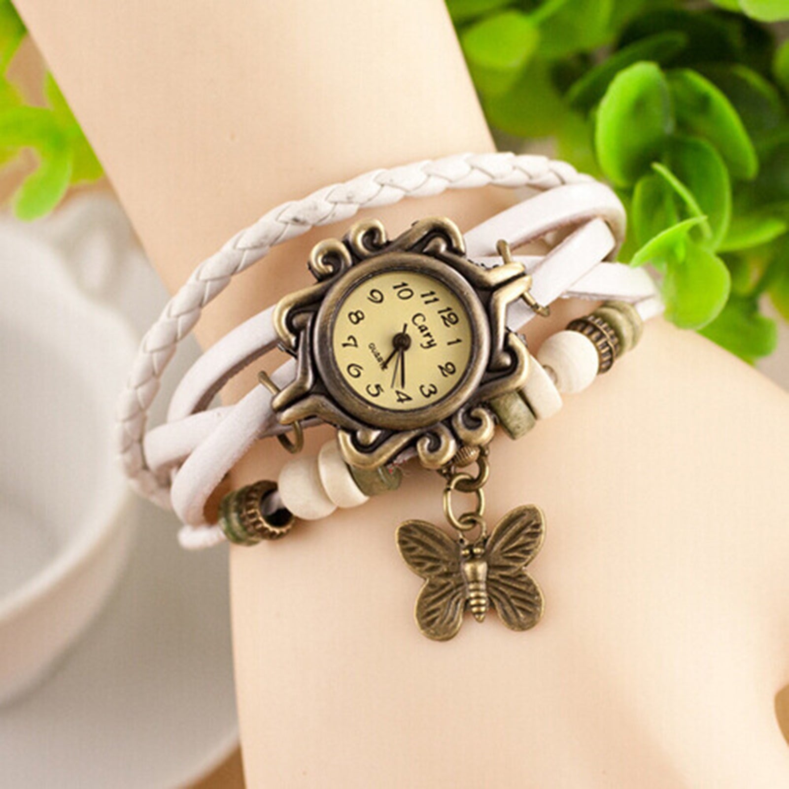White braided bracelet with a vintage-style watch and butterfly charm on a wrist.
