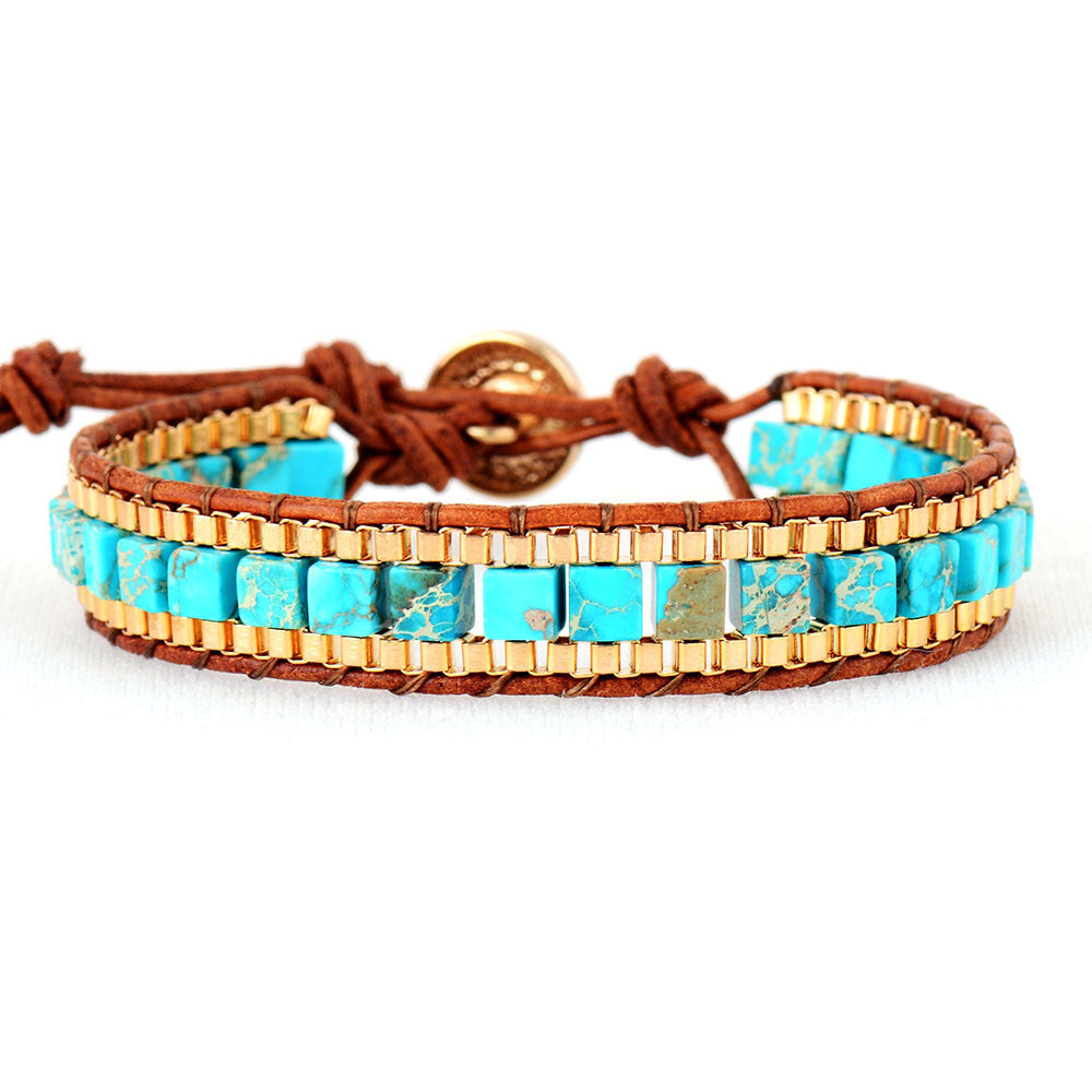 Turquoise and gold beaded bracelet with brown leather strap on a white background