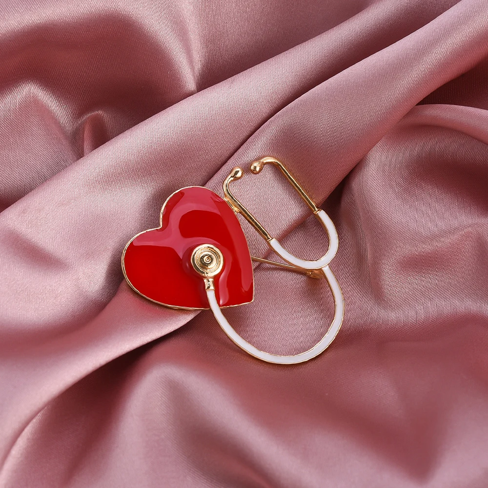 Heart-shaped red and gold brooch on pink fabric