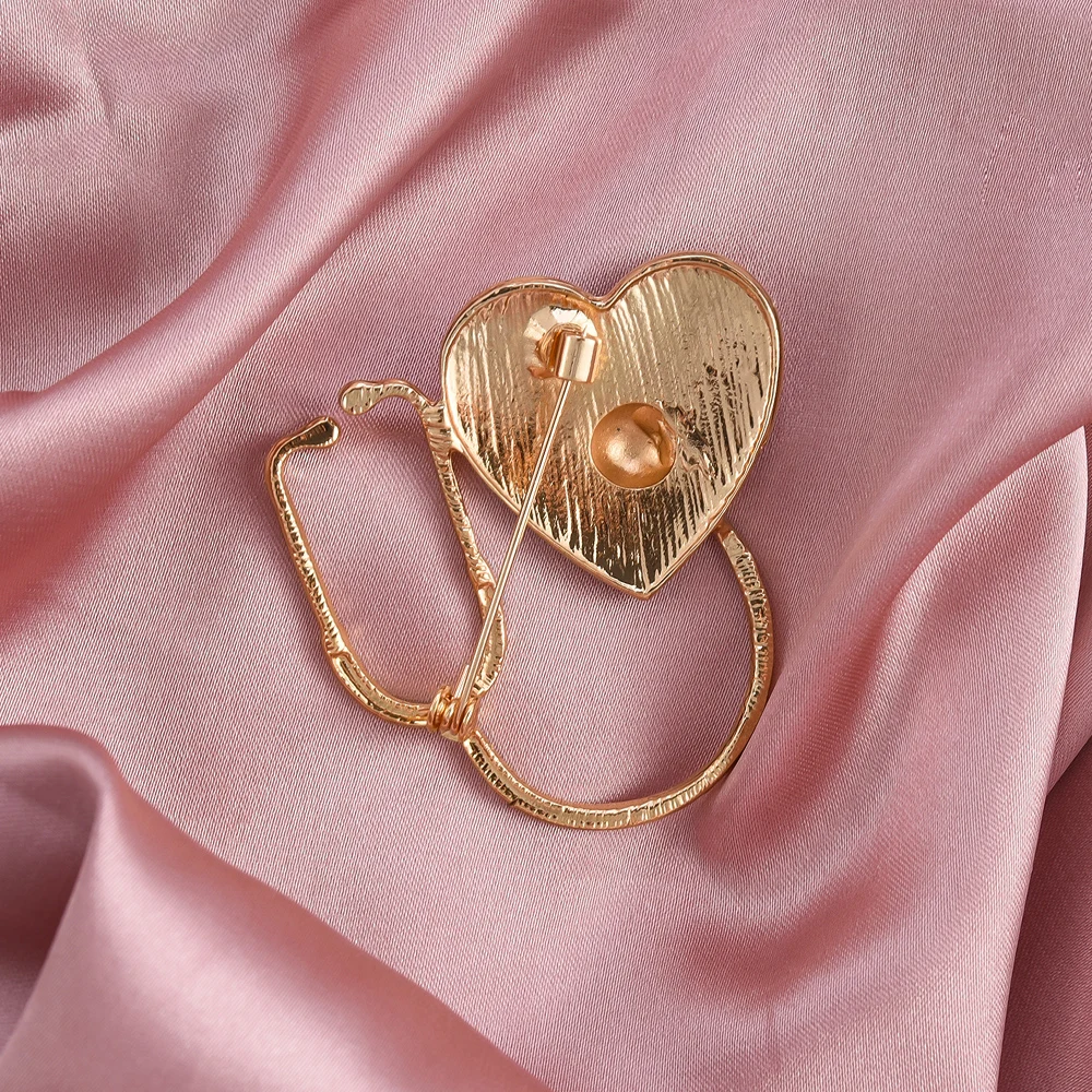 Gold heart-shaped brooch on a pink satin background