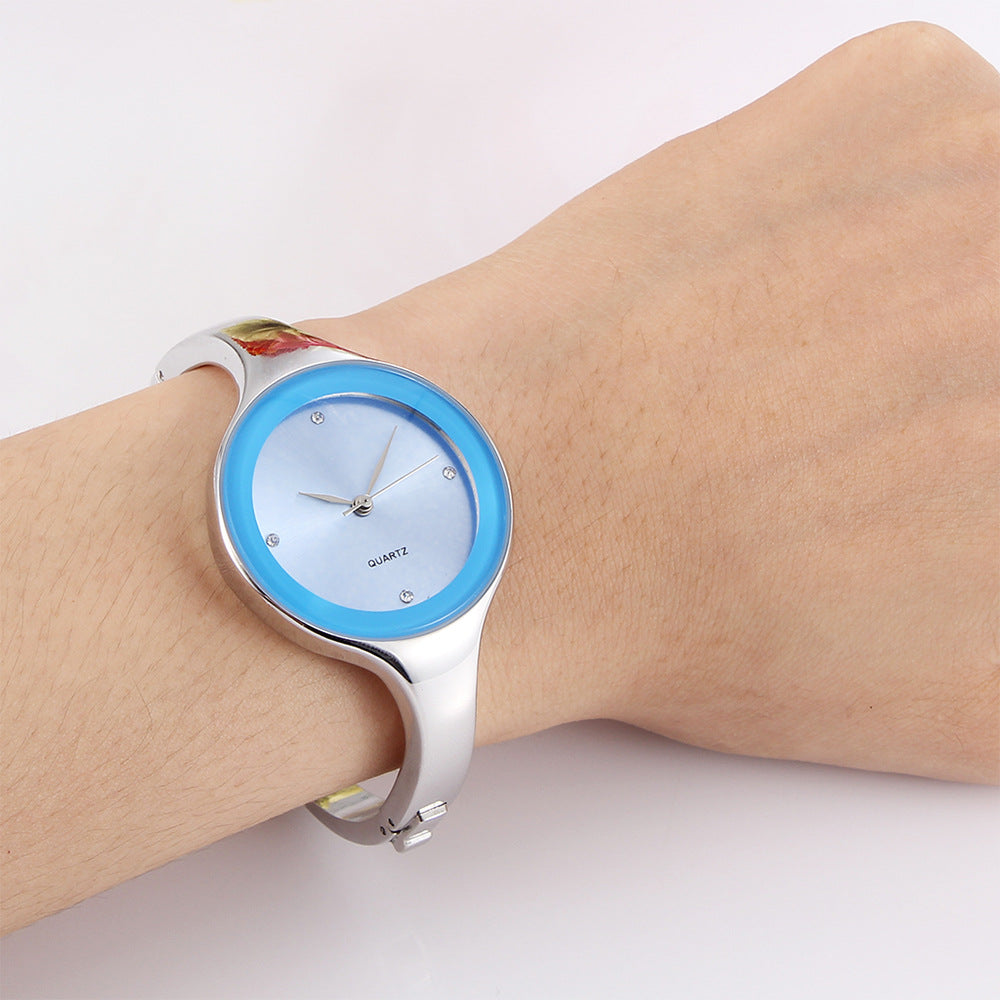 Wristwatch with blue face and silver band on a wrist against a white background