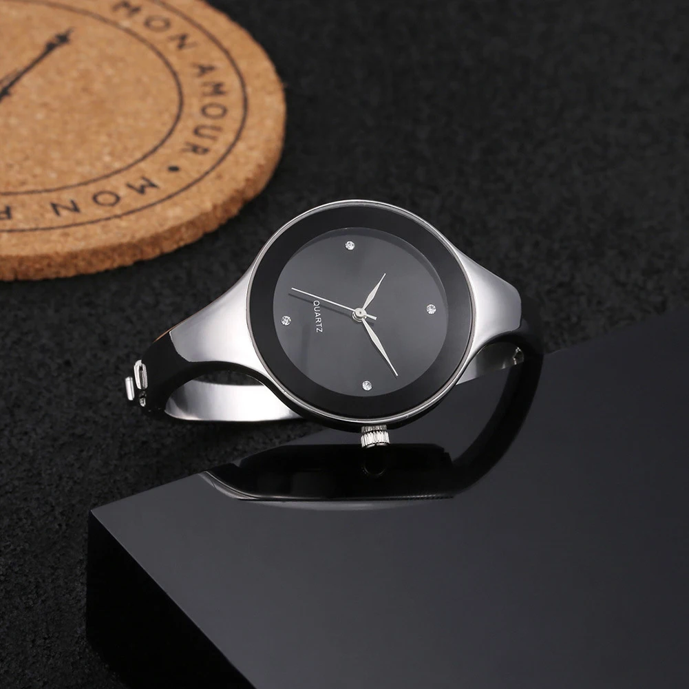 Silver watch with black face on a dark surface