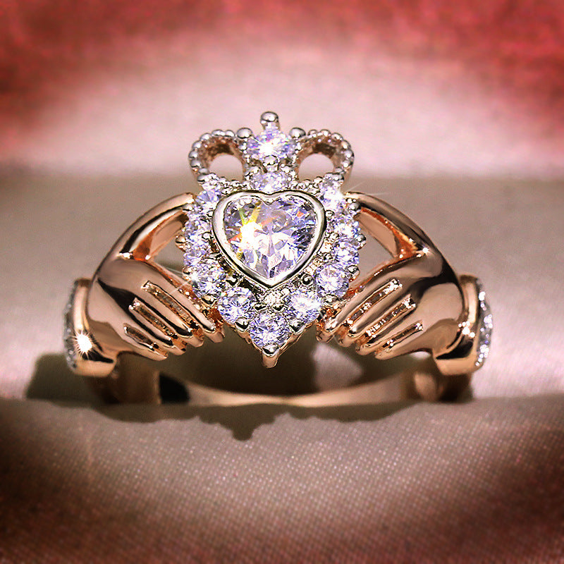 Rose gold ring with heart-shaped diamond and crown design on a soft background