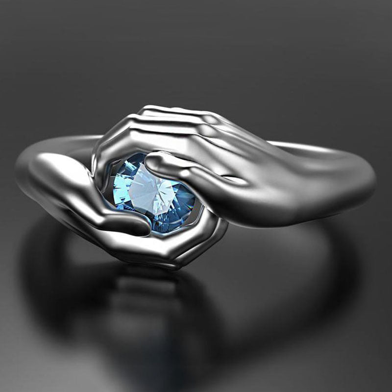 Silver ring with a blue gemstone on a dark background