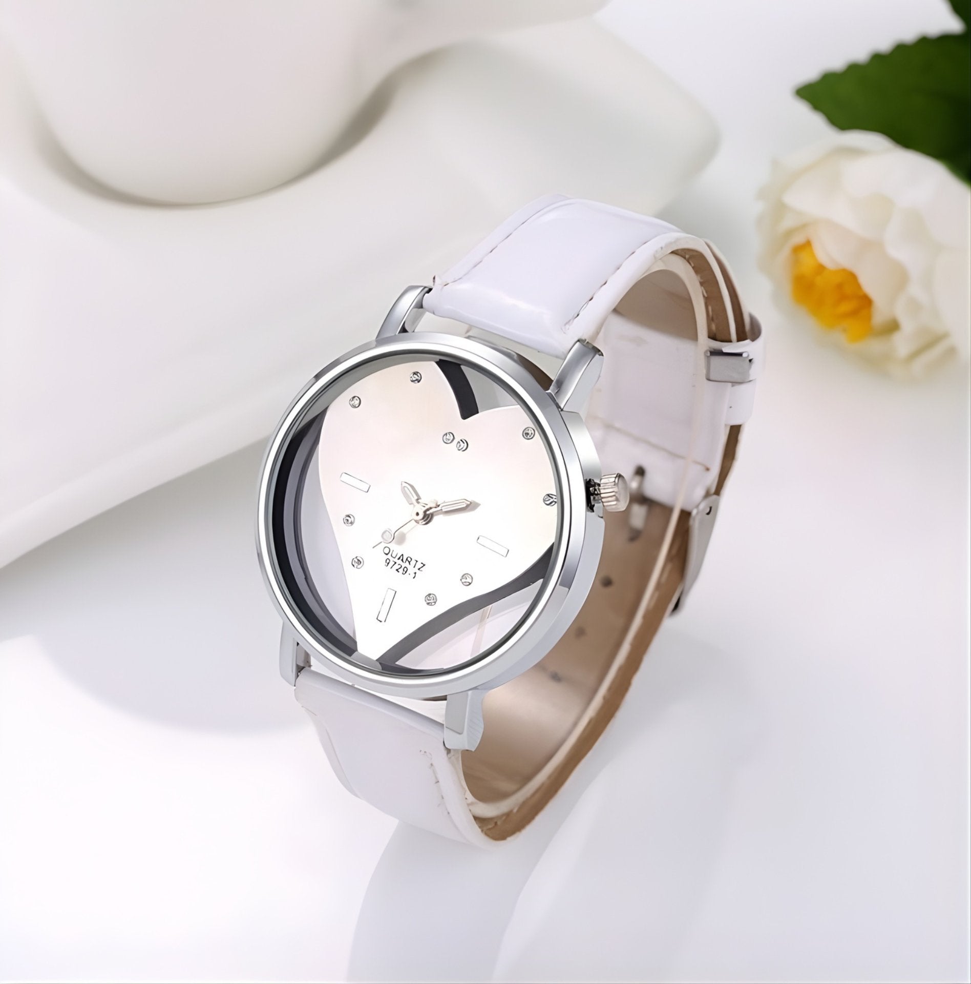 White wristwatch with a floral design on the dial, placed on a white surface with a flower in the background.