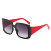 A pair of square oversized sunglasses with a bold retro chic design, featuring a black and red frame and pink lenses, displayed on a marble surface.