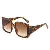 A pair of square oversized sunglasses with a bold retro chic design, featuring a leopard frame and tea lenses, displayed on a marble surface.