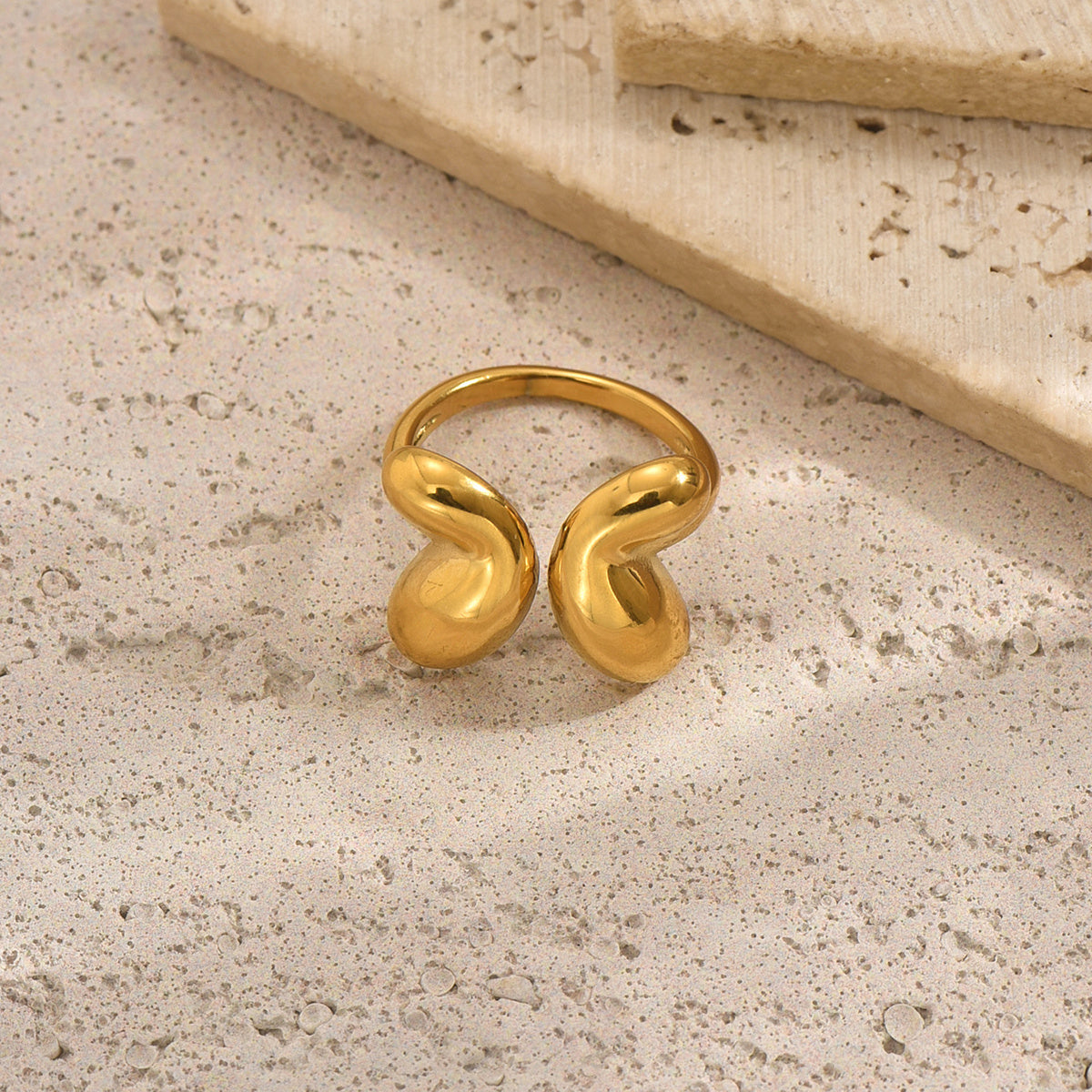 tiktok trendy Gold ring with a unique design on a textured beige surface