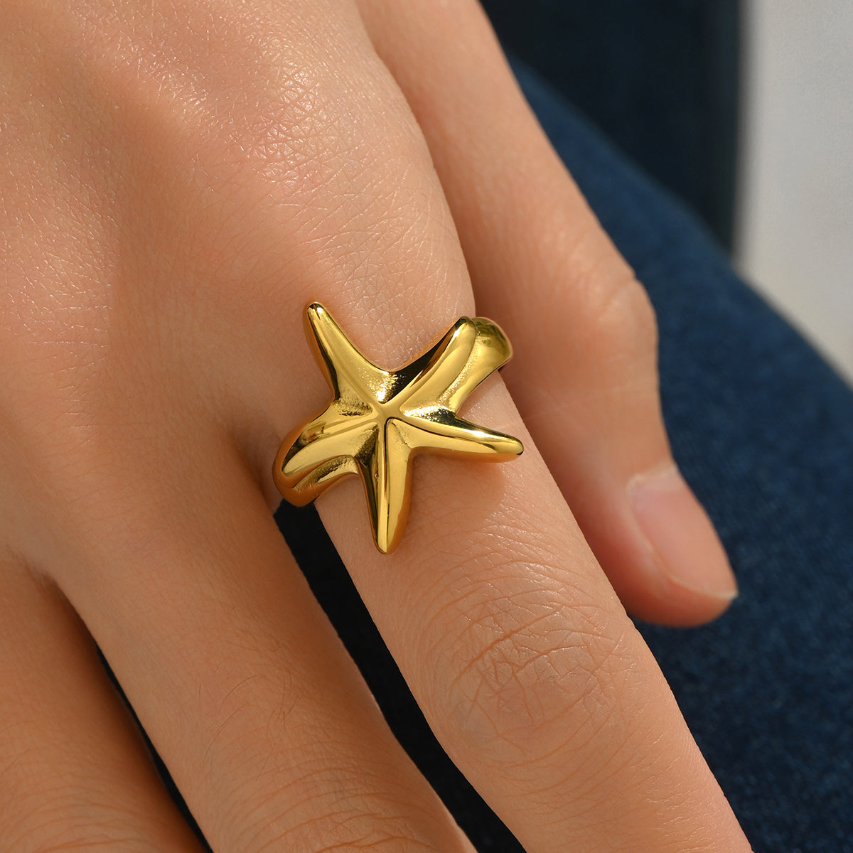 Gold star-shaped ring on a person's finger with a blurred background