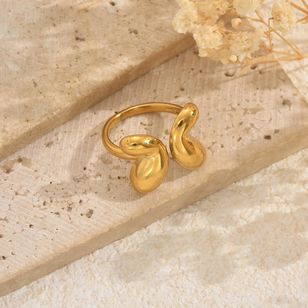 TikTok trendy Gold butterfly ring on a textured beige surface with dried flowers