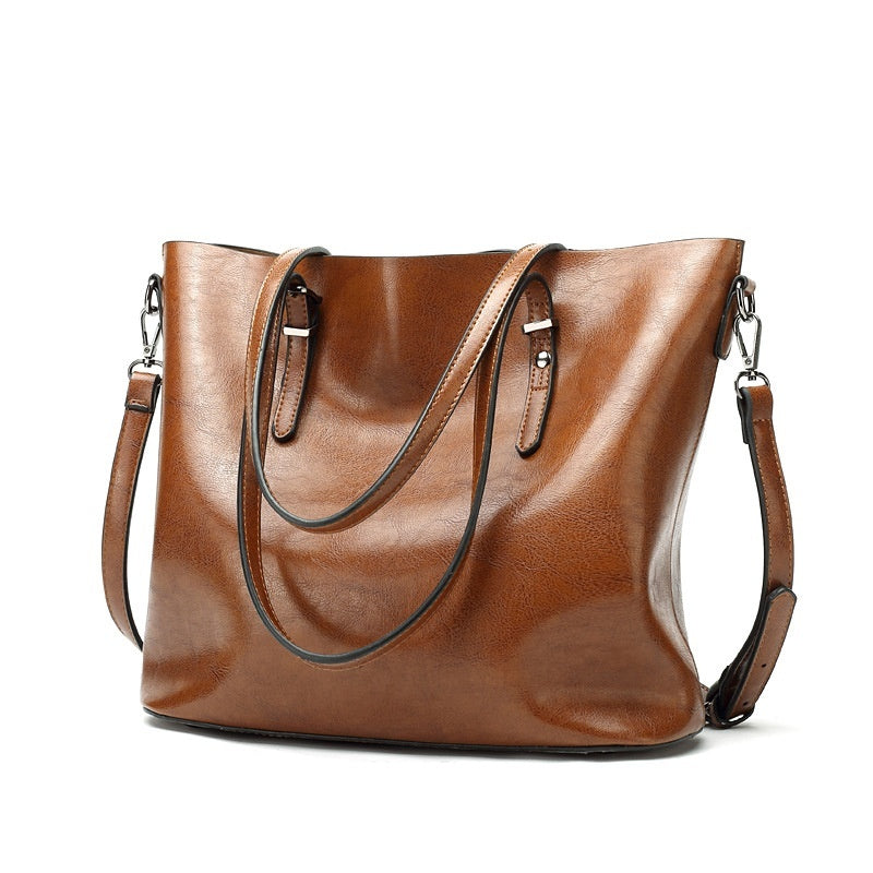 Brown leather handbag with a shoulder strap on a white background