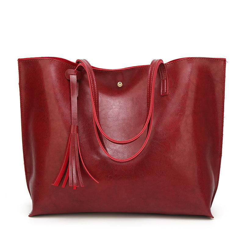 Red leather tote bag with tassel on a white background