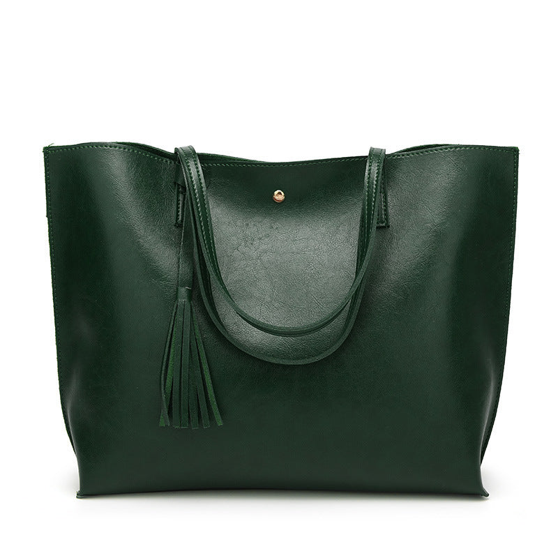 Green leather tote bag with a tassel on a white background